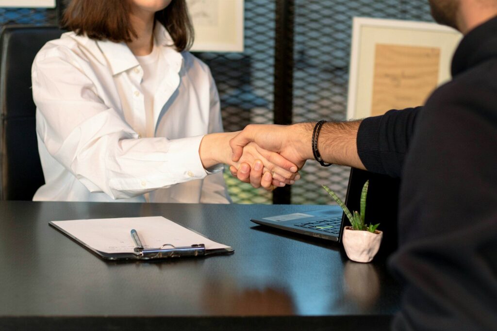From Accident to Justice: A Journey Through the Injury Law Process 7 a man and a woman shaking hands in front of a laptop