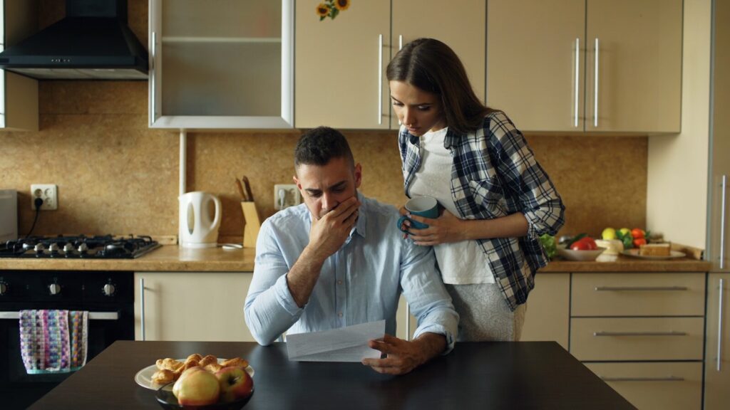 From Accident to Justice: A Journey Through the Injury Law Process 9 Couple looking stressed over bills at kitchen table.